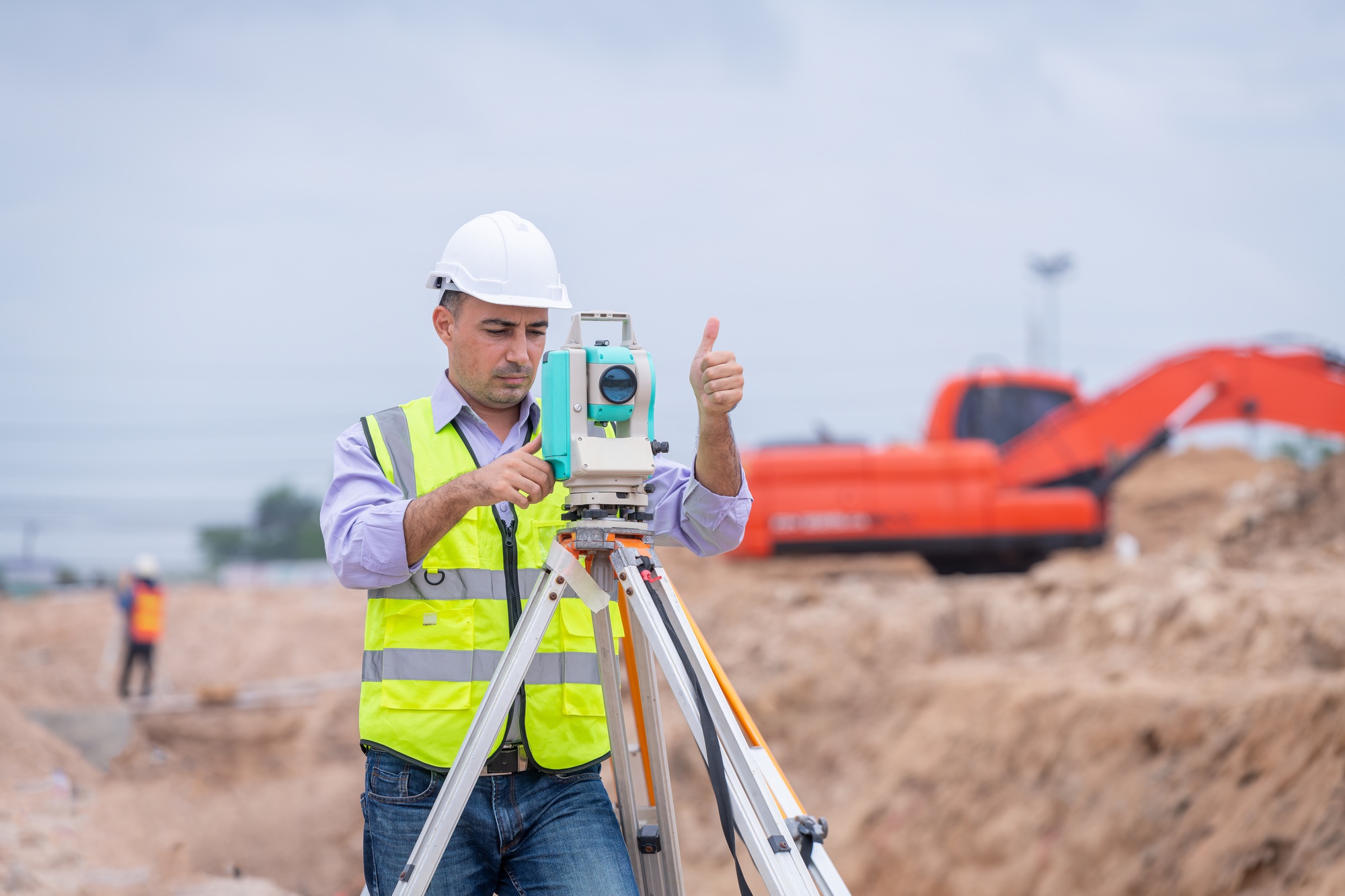 Surveyor engineers wearing safety uniform ,helmet and radio communication with equipment theodolite